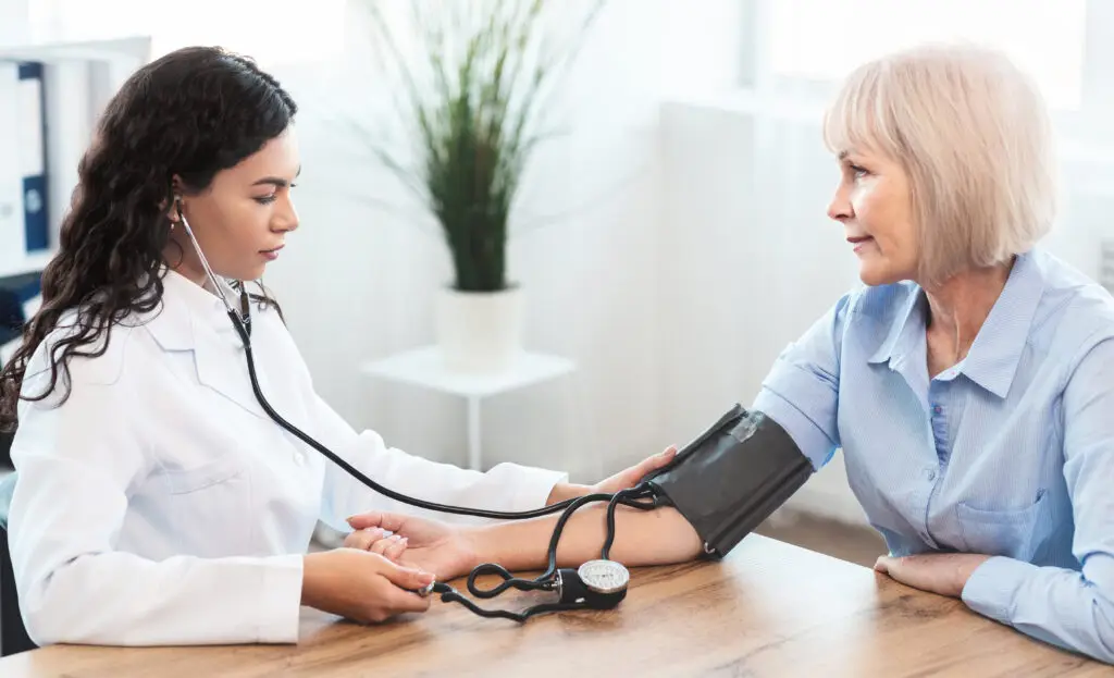 Healthcare provider checking an older adult’s blood pressure. 